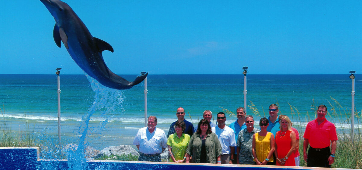 FAA team stands behind tank as dolphin leaps through air above