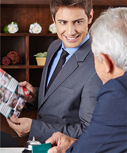 Young man shows older man brochure over hotel desk