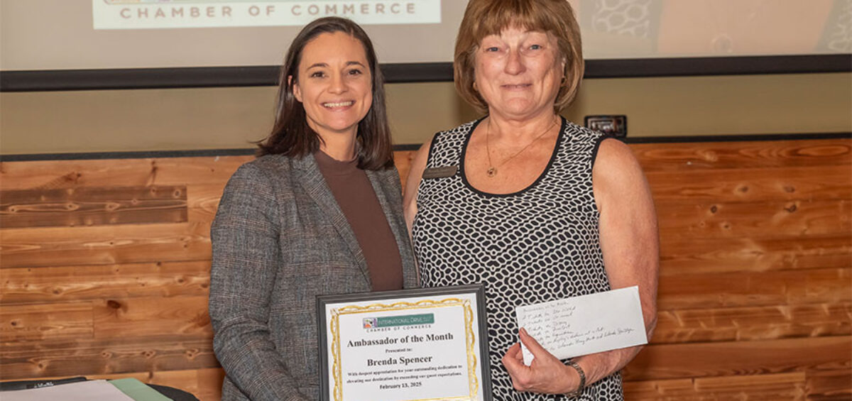 woman handing award plaque to woman on dais with projector