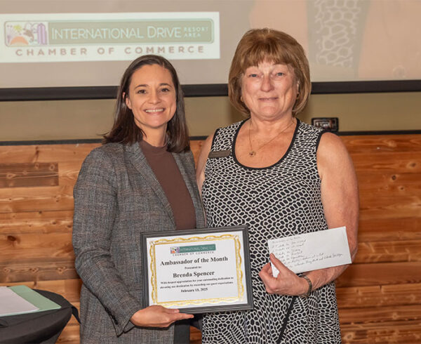 woman handing award plaque to woman on dais with projector
